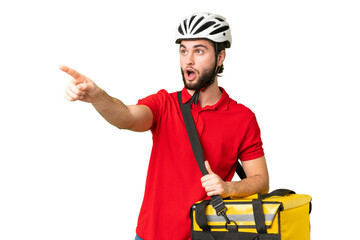Young delivery man with thermal backpack over isolated chroma key background pointing away