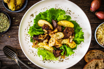 Fried liver with apples and onion on wooden table
