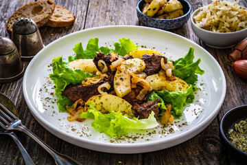 Fried liver with apples and onion on wooden table
