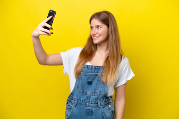 Young caucasian woman isolated on yellow background making a selfie