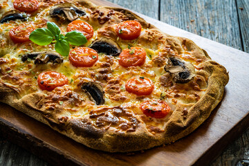 Pinsa Romana with mozzarella and vegetables on wooden table
