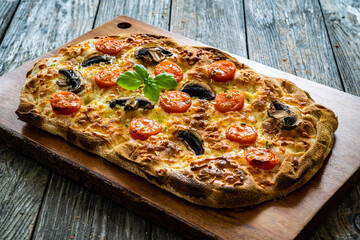 Pinsa Romana with mozzarella and vegetables on wooden table
