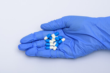 Lekarstwa trzymane w dłoni w niebieskich rekawiczkach
