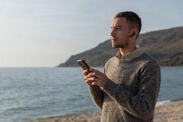 young man in shirt using cell phone on the beach with sunset