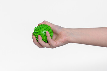 Zielona piłka z kolcami przeznaczona do rehabilitacji trzymana w dłoni