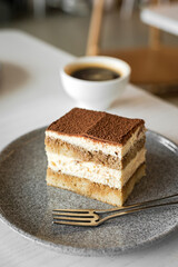 Tiramisu dessert cake and cup of black coffee at the table of a cafe