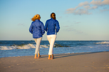 Two middle-aged women walking on beach
