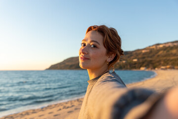 Fototapeta na wymiar redhead woman taking a selfie on the beach