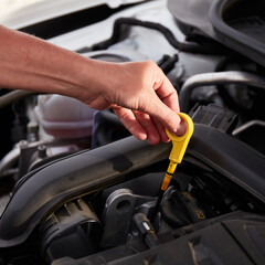 Obraz premium Checking engine oil. A woman's hand holding an oil bayonet in a modern popular car.
