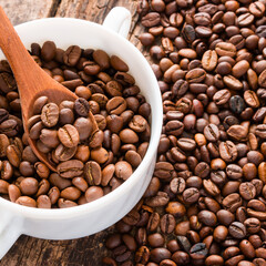 coffee beans on a table in a white cup with a wooden spoon
