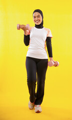 Naklejka premium feminine muslimah working out using dumbbells on a yellow background