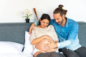 Caucasian man stroking unborn baby through tummy of his pregnant wife on the bed in bedroom. Family...