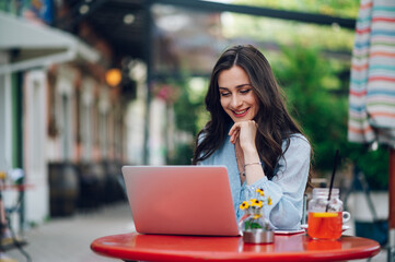 Beautiful woman sitting in a street cafe and using a laptop