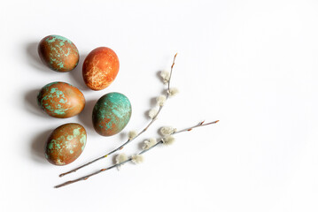 Easter composition of colored chicken eggs and twigs of pussy willow on a white background