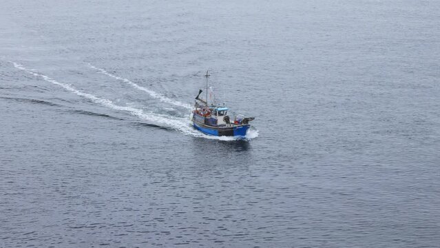 Small Fishing trawler travels across calm grey sea in Cornwall, UK