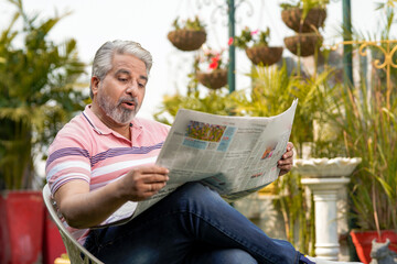 Old man reading news paper and giving shocking expression. lifestyle concept.