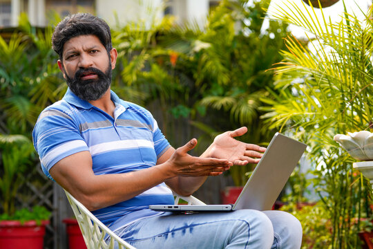 Indian man sitting at outdoor and using laptop