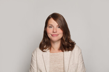 Obraz premium Studio portrait of smiling positive cheerful business woman in white casual suit