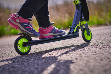 A girl rides and brakes with her foot the rear wheel of a scooter on a rollerdrome with an asphalt. © Ramon