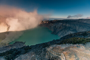 Sunrise over Kawah Ijen Volcano revealing acid turquoise lake and toxic sulfur gases next to illegal mining operation, Java, Indonesia