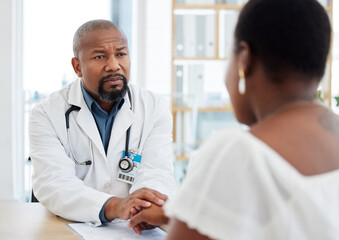 Serious doctor, patient and holding hands in consultation for bad news, cancer diagnosis or comfort. Healthcare, black man and medical professional with woman for help, support and empathy in clinic.