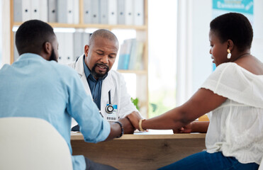 Doctor, black couple and holding hands in consultation clinic, support and comfort. Healthcare, obstetrician and man and woman talking with medical professional for advice, fertility treatment or ivf