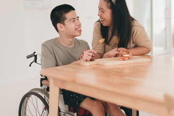 Asian mother teaches teenage boy to take spoon,fork and practice eating on his own in home with smile face, caring for love, positive energy,concept of coexistence,Happy with myself,family Caregiving.