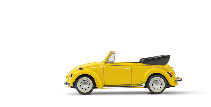 Model of yellow retro toy car cabriolet on white background. Miniature car side view with copy space