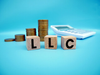 LLC (Limited Liability Company) acronym on wooden cubes on a gray background with a calculator and...