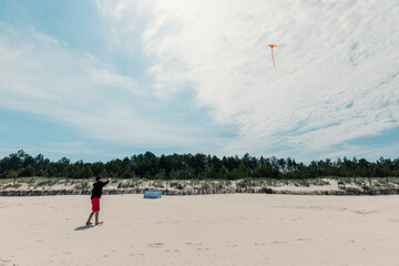 Obraz premium Boy flying kite on the beautiful sandy beach at Baltic Sea, Poland