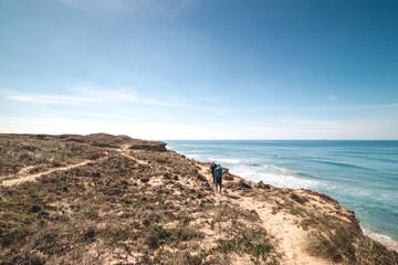 Fototapeta na wymiar Passionate adventurers walk the rugged, dry coastline with cliffs around the Atlantic Ocean on a trail called the Fisherman Trail in Portugal