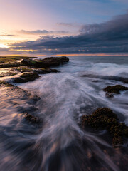 Water flowing between rocks at the beach coastline.
