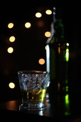glass of whiskey on black background with lights 