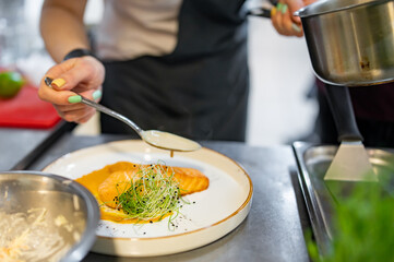 Chef cooking Roasted salmon steak with pumpkin cream on restaurant kitchen