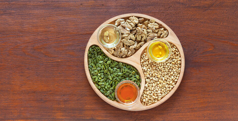 Three types of healthy organic vegetable oil - from pumpkin seeds, from cedar nuts and from walnuts. on wooden background. Vegetable oils containing essential polyunsaturated omega 3 and omega 6 acids