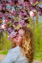 Fototapeta premium sensual seductive mature sexy redhead woman portrait in white dress surrounded by japanese cherry blossoms
