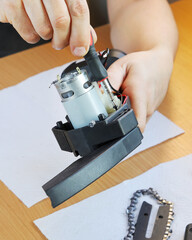 Repair, Hands fix new electric engine in chain saw body