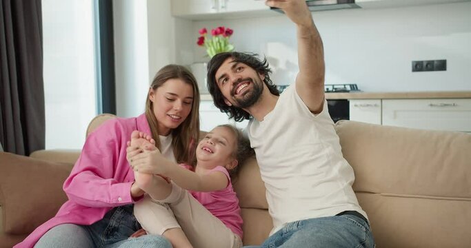 Photo of cheerful family with small daughter, a man make selfie record video
