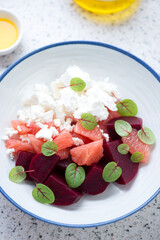 Salad with beetroot, feta cheese and grapefruit in a white plate, vertical shot, selective focus, closeup