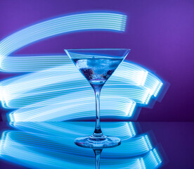 Martini cocktail in a glass against the background of neon lights