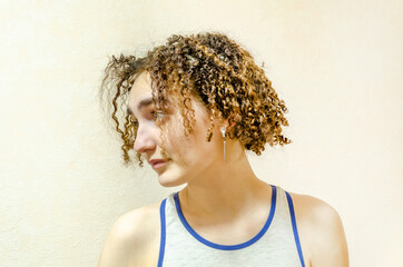 close-up young woman, short blonde hair with curls. Portrait of cute, funny girl on beige background