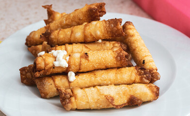 Fried Turkish cigarette shaped rolls on plate. Oily or fatty food concept idea. In native language: Sigara Böreği in Turkish.