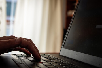 Persona escribiendo con el teclado de su laptop. Fotografía con desenfoque selectivo
