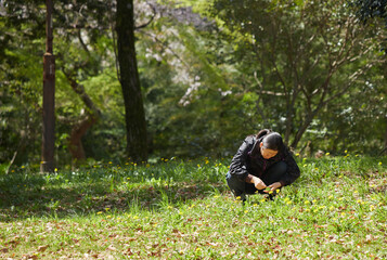 春の公園で野草を取る母親の姿