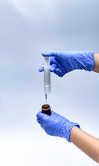 Badanie próbki w laboratorium - strzykawka, fiolka, niebieskie rękawiczki nitrylowe na białym tle