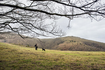 Fototapeta premium Young couple hiking or trekking in the Ibardin Valley in the Basque Country with their young dog