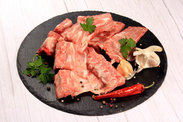 Raw pork meat bones with meat on a black stone plate