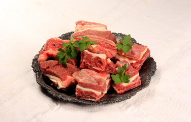 Raw beef ribs on a metal plate, white background