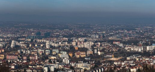 Fototapeta premium Panoramic view of Banja Luka city during sunny day, air pollution in city, distant hills fade in haze