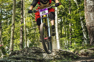 close-up male rider on downhill bike riding forest trail, racing DH mountain bike, extreme sport games